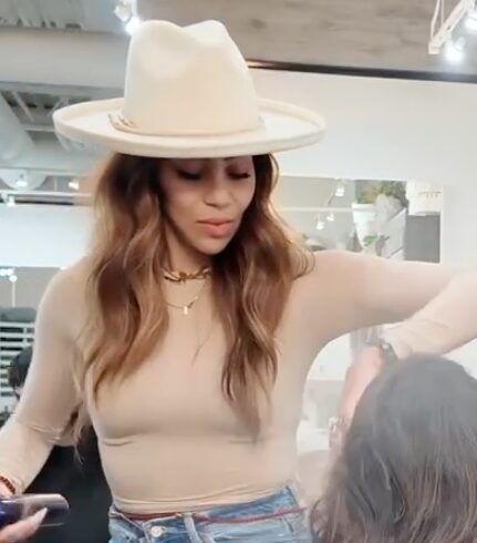 Garnish founder Candice Mot rocks a wide-brimmed hat with extensions while styling a guest's hair